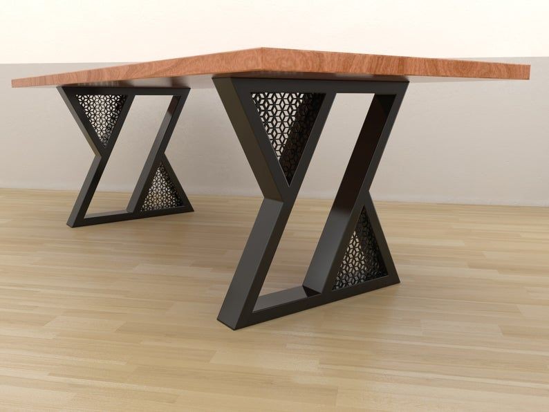 A high-quality 4:3 image showing a wooden dining table with unique, geometric black metal legs, set against a simple neutral background.