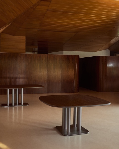 A high-end, 4:5 ratio ad creative focusing on the architectural form of a modern dining table in a warm, wood-toned interior space.