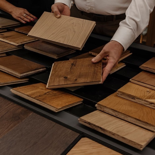 A close-up shot showing a professional expert presenting high-quality hardwood flooring samples, emphasizing texture and material variety.