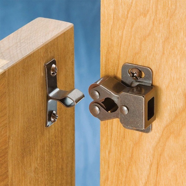 A close-up, high-resolution image of a double roller catch hardware piece installed on a wood surface, focusing on the mechanism's simplicity.