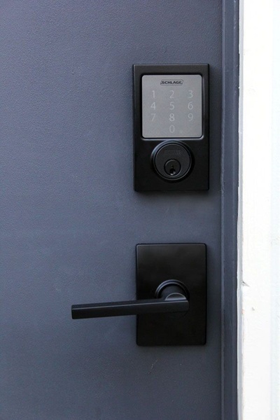 A clean, high-contrast shot of a black smart door lock installed on a dark grey door, emphasizing modern home aesthetic.