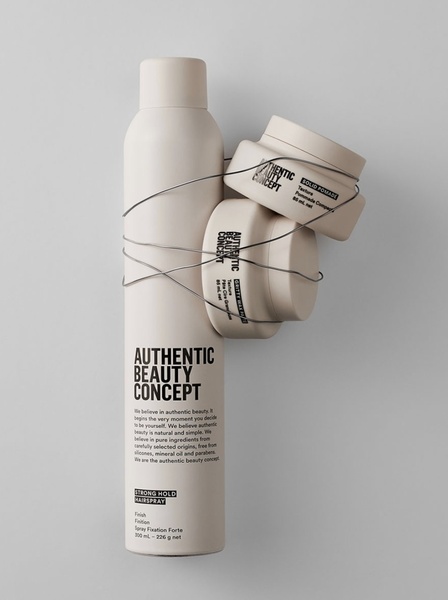 A clean, studio-lit creative showing a hairspray bottle and two pomade jars stacked and tied with wire to emphasize a minimalist brand aesthetic.