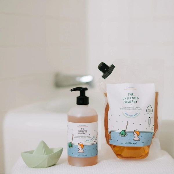 A clean, bright studio photograph featuring a pump bottle of kids shampoo next to its eco-friendly refill pouch, emphasizing sustainability and simplicity.