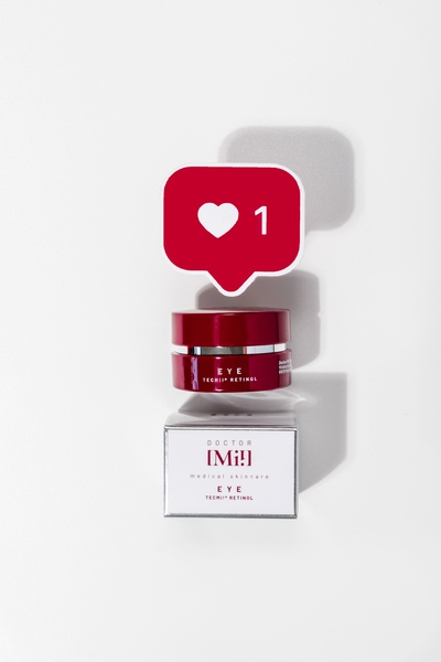 A minimalist studio shot featuring an eye cream jar topped with a digital like icon, symbolizing high engagement and product appeal.