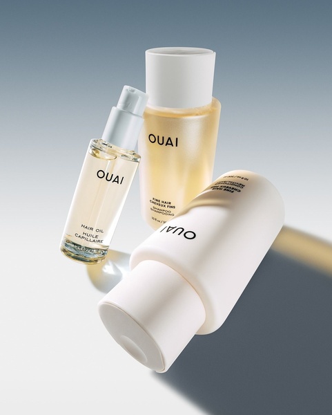 A high-end studio shot featuring three hair care products arranged in a clean, soft-lit composition to highlight premium branding.