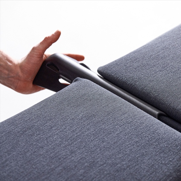 A close-up shot showing a hand interacting with the mechanism of a dark gray sofa bed, highlighting the furniture's build quality.
