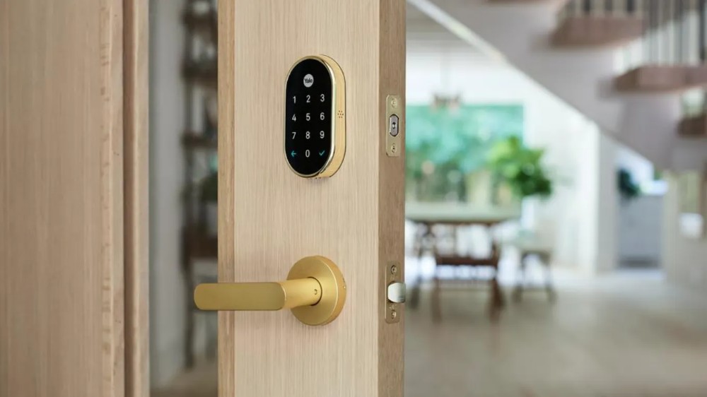 A high-end smart lock and matching handle set showcased on a clean, light oak door in a bright, modern interior.