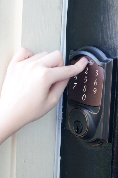 A focused close-up shot showing a finger entering a code on a digital keypad, highlighting the intuitive installation and daily utility of a smart lock.