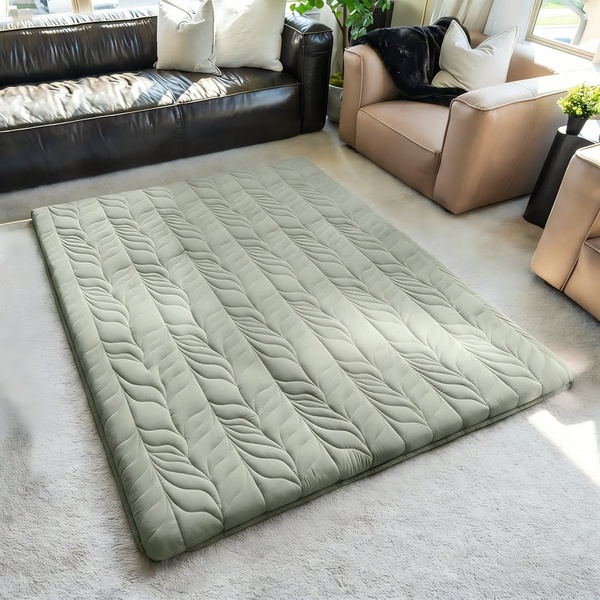 A high-quality, 1:1 square format ad creative showcasing a sage green floor mattress in a clean, modern living room setting.