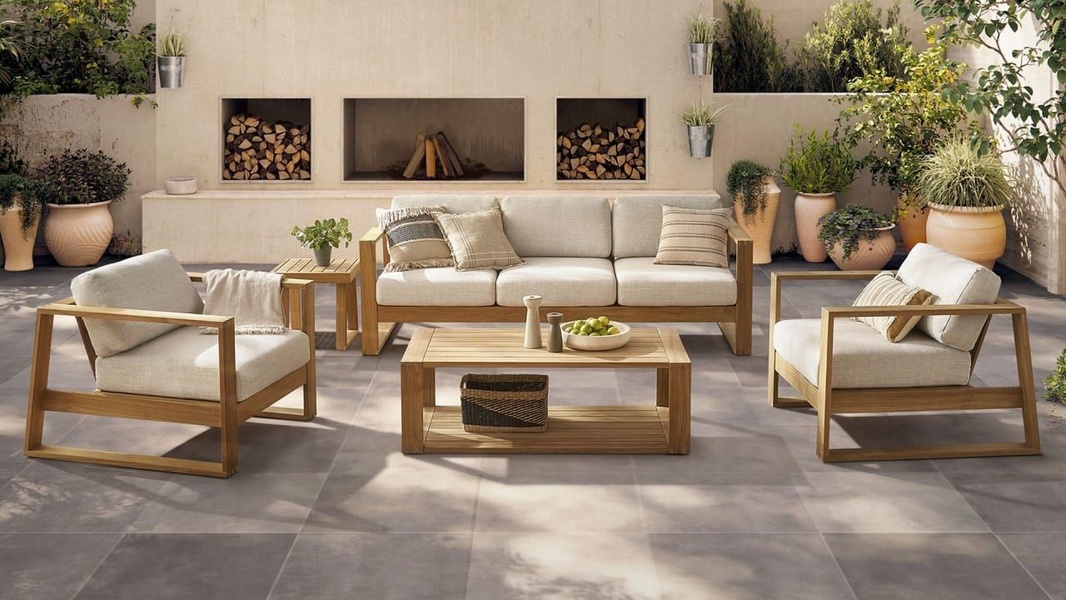 This creative showcases a high-end, matching teak wood and neutral fabric sofa set in a serene, curated outdoor patio environment.