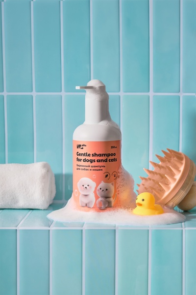 A clean, high-contrast product shot of pet shampoo surrounded by soap bubbles and bathroom accessories, focusing on gentle, trustworthy branding.