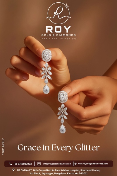 A close-up photograph featuring a model holding delicate, dangling diamond earrings, highlighting craftsmanship and luxury.