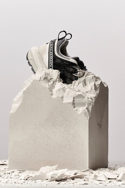 A high-contrast studio shot of a technical running shoe perched atop a jagged block of raw stone, emphasizing durability and texture.