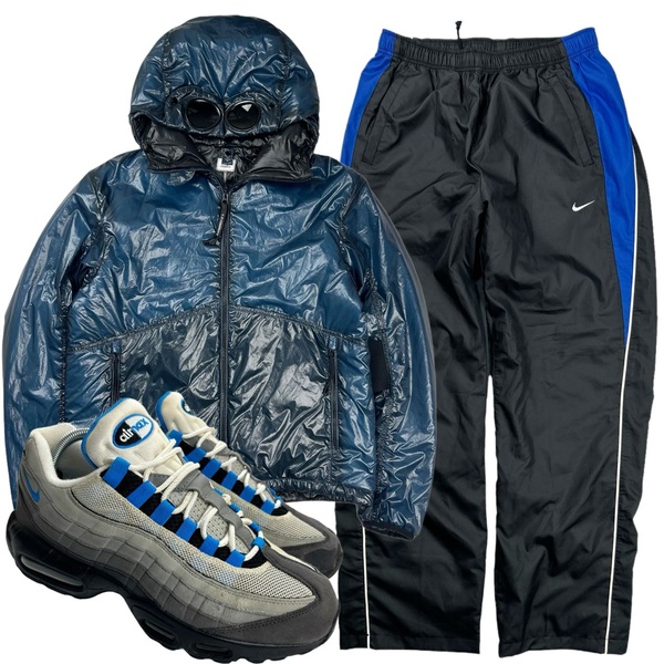 A clean, studio-lit display of a matching streetwear outfit featuring a technical jacket, track pants, and sneakers against a white background.