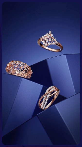 A high-end, studio-style shot featuring three unique rose gold rings displayed on geometric, deep blue architectural blocks.