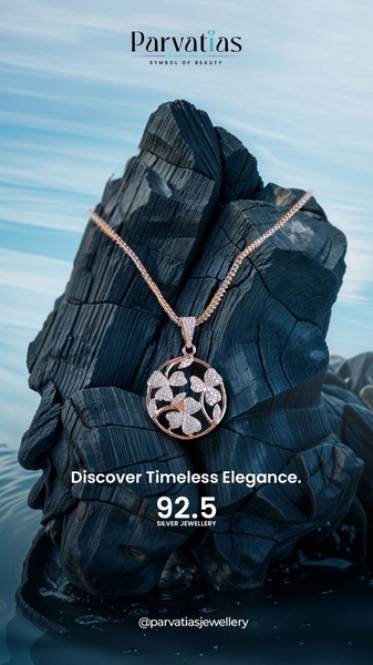 A high-contrast 9:16 vertical creative showcasing a delicate silver pendant resting on raw, black charcoal blocks against a soft blue background.
