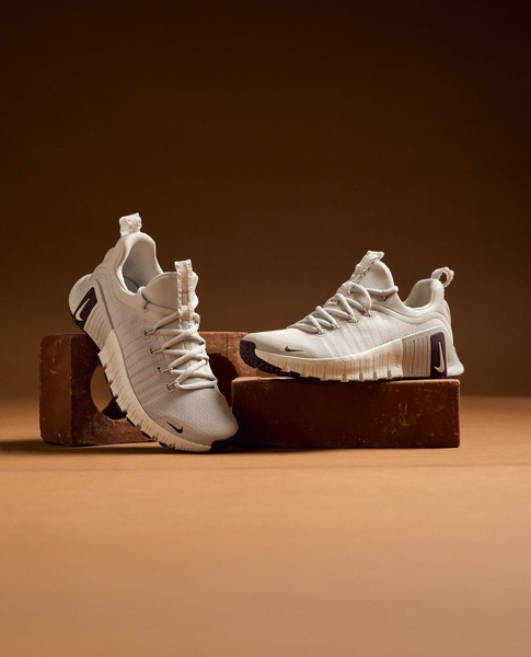 A clean, studio-lit photograph featuring a running shoe perched on bricks, using natural textures and earth tones to ground the product.