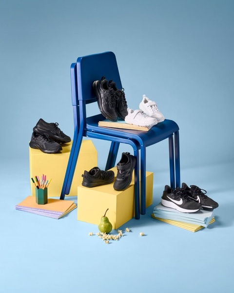 This creative showcases multiple running shoes arranged on a blue chair and yellow blocks, using color blocking to highlight the product range.