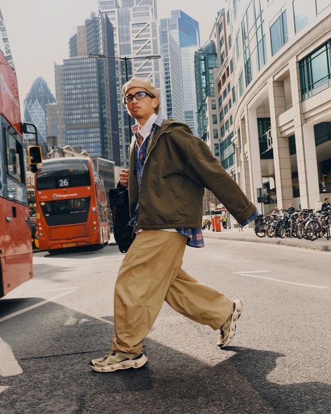 A high-fashion urban portrait of a model crossing a city street, emphasizing the product sneakers in a natural, high-energy environment.