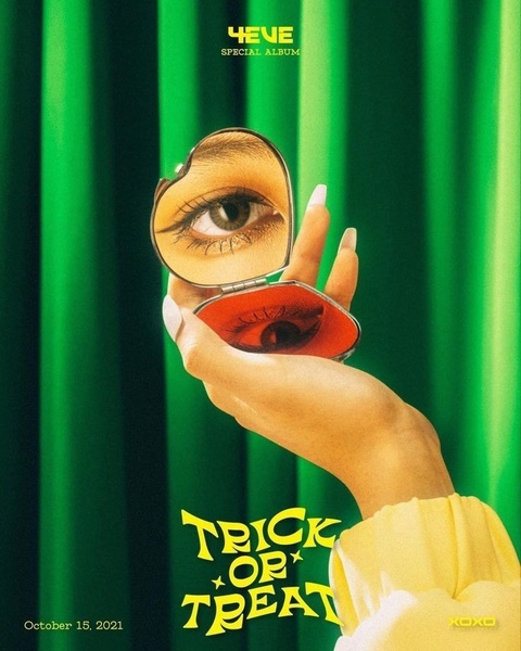 A close-up shot of a hand holding a compact mirror, reflecting one eye while the other eye is seen on the mirror surface in a deep red tone against a vivid green curtain.