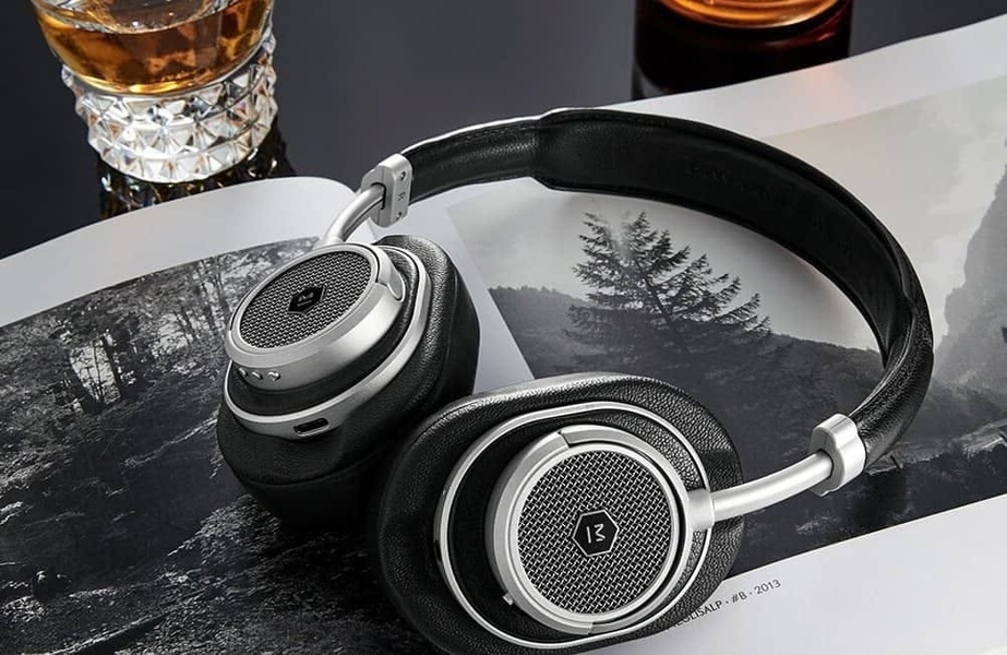 A high-end, clean product shot of headphones placed on a book next to a glass of whiskey, emphasizing sophistication and quality.