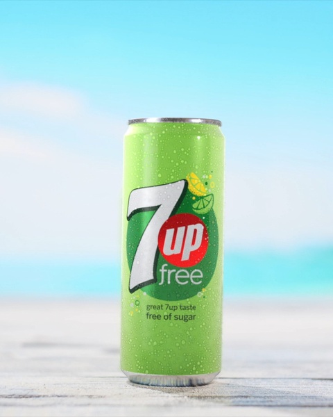A high-clarity, vertical product shot of a 7Up Free can centered against a vibrant, natural beach background.