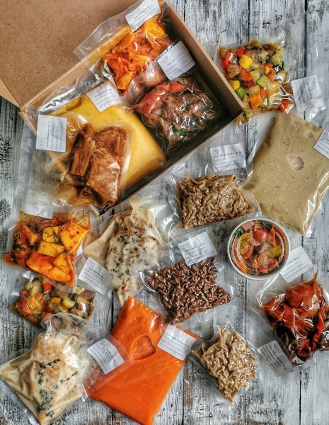 A top-down view of vacuum-sealed meal kit components arranged neatly on a rustic wooden table, emphasizing freshness and variety.