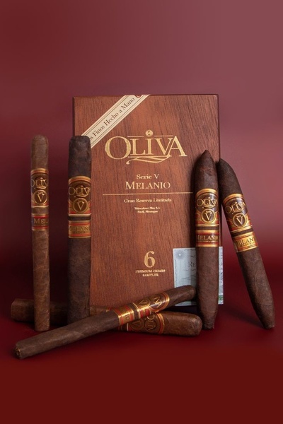 A refined product hero shot featuring a branded box and multiple cigars, set against a deep maroon backdrop to convey luxury.