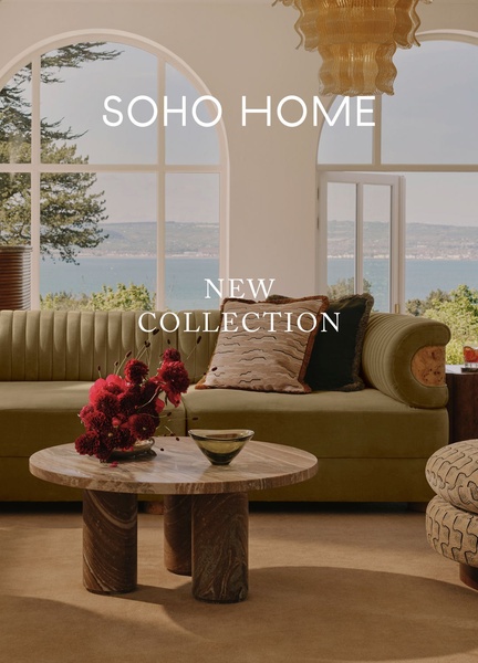A high-end editorial shot featuring a velvet sofa, coffee table, and scenic window view, emphasizing a sophisticated brand collection.