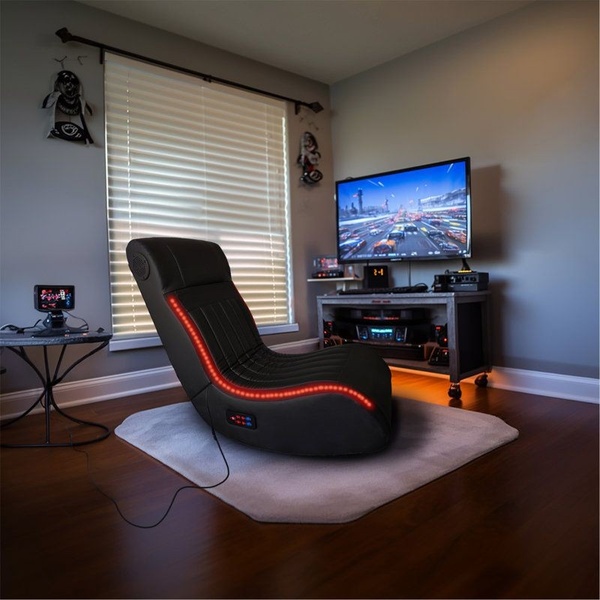 This creative centers on a black gaming floor chair placed in a stylized bedroom, using red RGB lighting to create a focused, high-energy atmosphere.