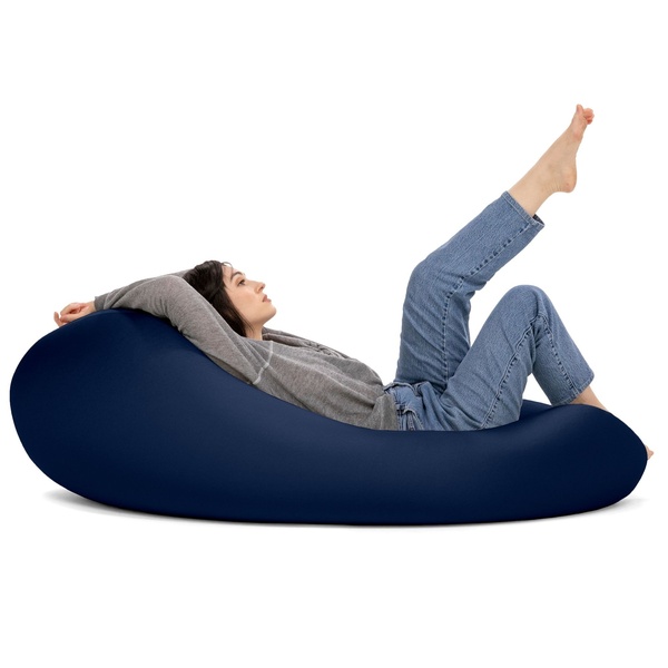 A clean, studio-lit shot of a person relaxing on a navy blue bean bag chair, emphasizing comfort through body language and negative space.