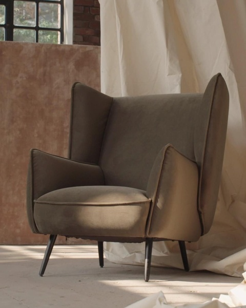 This creative showcases a single wingback chair in a soft, monochromatic, studio-style environment that emphasizes texture and premium design.