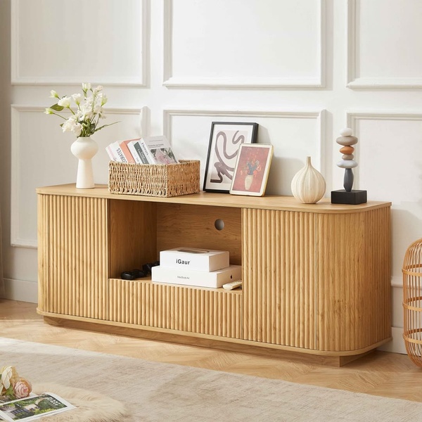 A high-quality, balanced shot of a wooden TV console with textured cabinet doors, styled with home decor in a bright, neutral room.