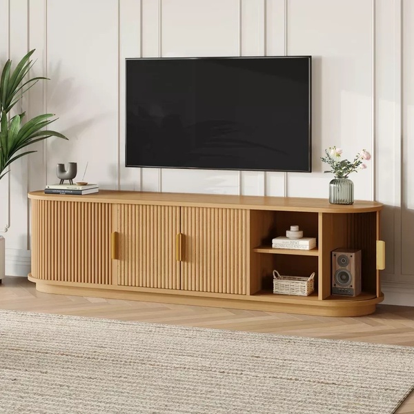 A high-quality, studio-lit photograph of a modern ribbed-wood TV media console featuring clean lines and a curated decor arrangement.