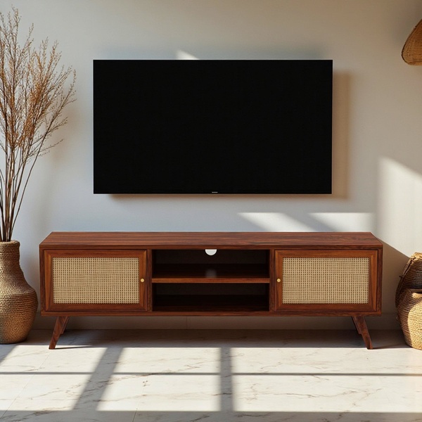 A high-end, clean product shot of a wooden media console featuring cane detailing, centered under a wall-mounted television in a sunlit room.