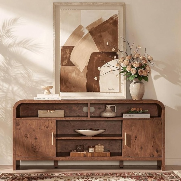 A high-end, editorial-style photograph of a walnut-toned media console featuring decorative styling, soft lighting, and an abstract art backdrop.