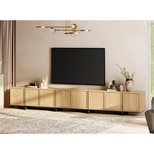 A high-end, clean studio-style photograph of a long, light oak media console in a neutral, modern living room setting.