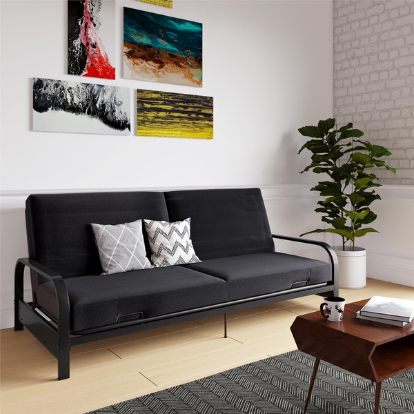 A high-quality, 1:1 ratio studio photograph featuring a black futon in a modern, light-filled living room setting.