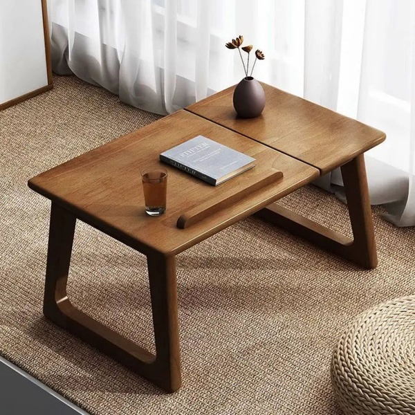 A high-quality product shot of a wooden folding laptop table staged in a bright, airy living room space with natural textures.