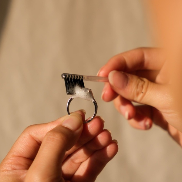 A close-up demonstration of a cleaning tool being applied to a silver ring, emphasizing the process and instant results.