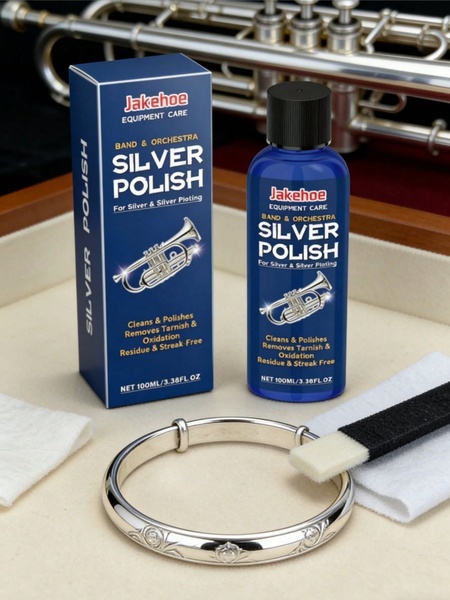 A high-quality product photography shot featuring silver polish bottles, a polishing cloth, and a trumpet in the background to demonstrate professional instrument care.