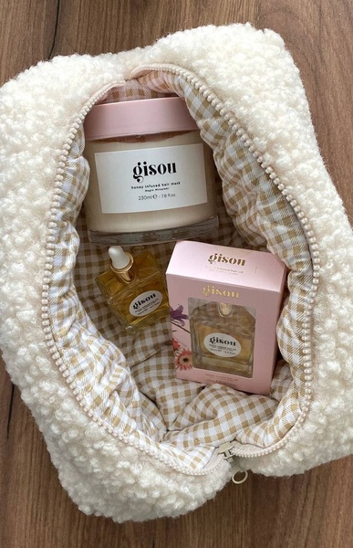 A high-quality top-down shot of hair care products tucked inside a cozy, textured pouch, showcasing brand aesthetic and premium positioning.
