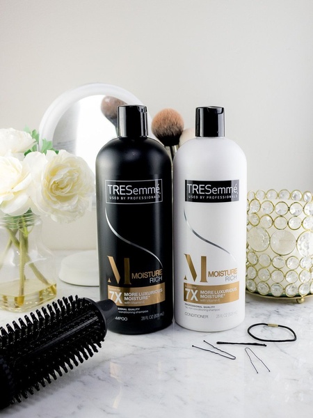 A high-quality, professional studio shot featuring matching shampoo and conditioner bottles alongside vanity accessories to communicate a premium beauty experience.