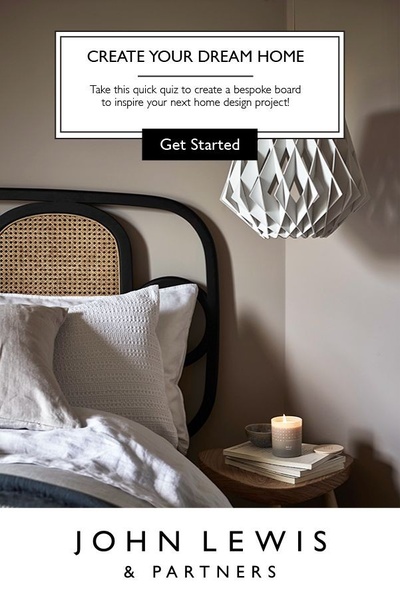 A clean, aspirational bedroom interior featuring a modern lamp and candle, prompting users to take a quiz for custom design inspiration.