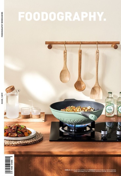 A high-quality lifestyle shot featuring a light green wok on a stovetop, balanced with wooden utensils and clean, bright kitchen surfaces.