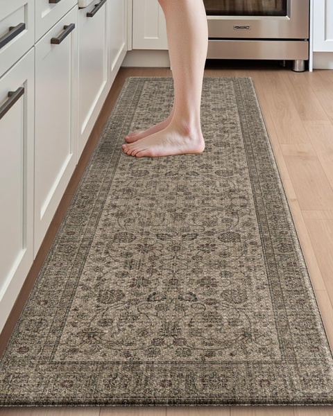A top-down, first-person perspective shot of a person standing on a decorative kitchen runner rug, emphasizing the texture and placement of the product in a home environment.