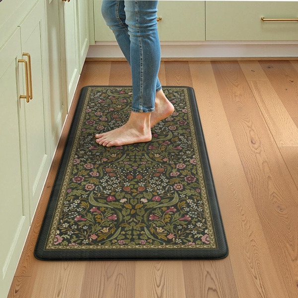 A high-angle, first-person perspective shot featuring a person standing on a decorative anti-fatigue kitchen mat in a modern kitchen setting.