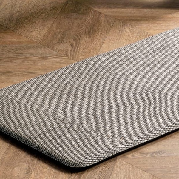 A high-quality, top-down angled shot of a textured anti-fatigue mat placed on a natural hardwood floor, emphasizing material quality and design.