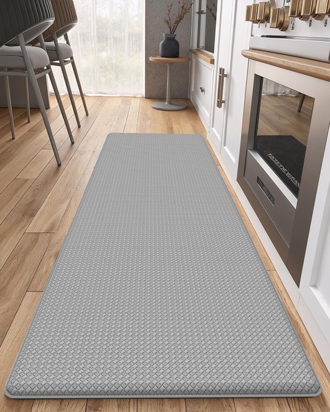 A high-quality, top-down perspective showing a grey textured anti-fatigue kitchen mat placed in a modern kitchen setting.