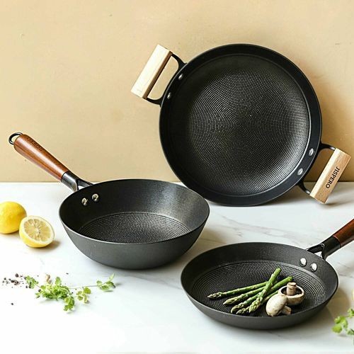 This creative utilizes a bright, clean, and airy studio environment to showcase a three-piece non-stick cookware set, emphasizing the textured surface and wood-finish handles.